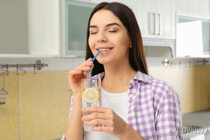 beautiful young woman drinking lemon water